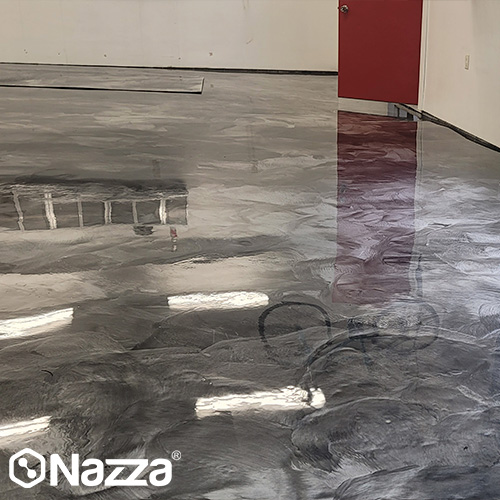 Suelo industrial de resina epoxi en tono gris con acabado continuo y alto brillo. Se aprecia un pavimento uniforme, sin juntas y con reflejo espejo, ideal como pavimento epoxi para naves, locales o espacios técnicos.